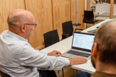 Zaakvoerder van Bitemark bespreekt digitalisering voor kmo’s tijdens een overleg aan tafel met presentatie op laptop.